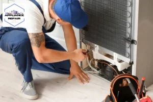 Worker repairing fridge in kitchen